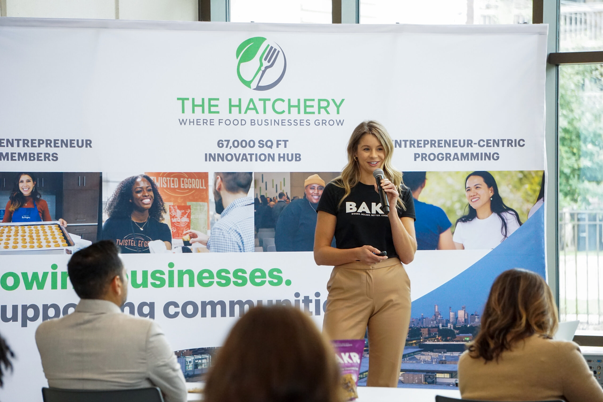 A lady giving a speech with a big sign behind her